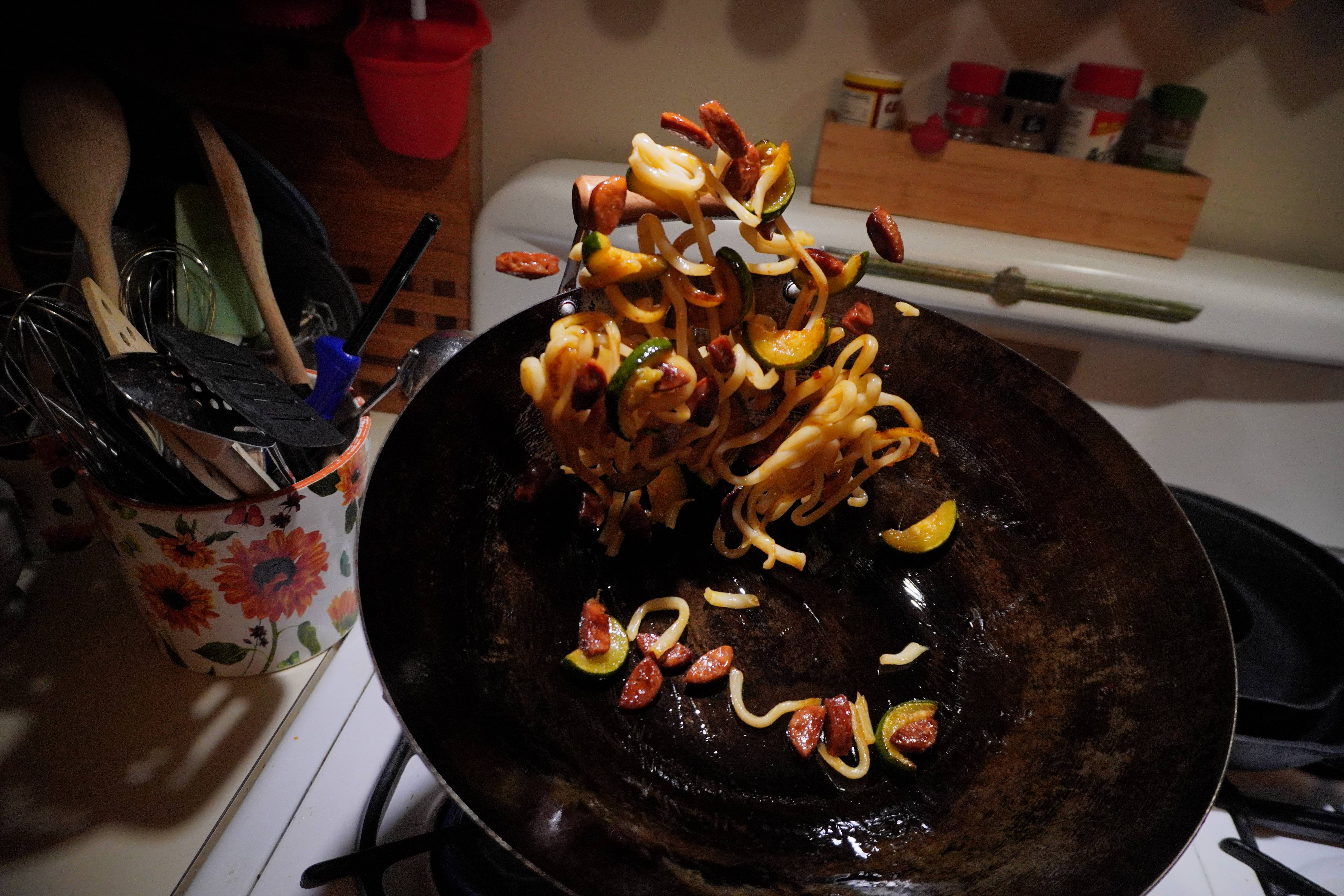 Noodles, veggies, and meat being tossed in a wok. Shot on Sony Alpha ZV-E10